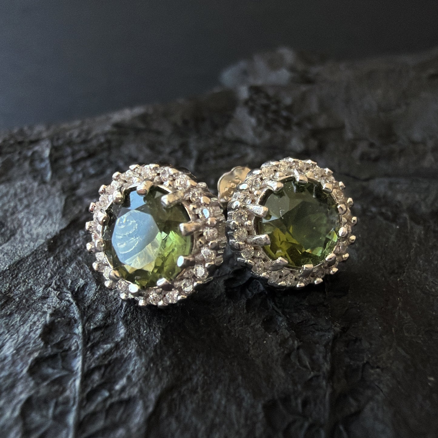 Pair of silver earrings with 6 mm Moldavites on a dark textured surface