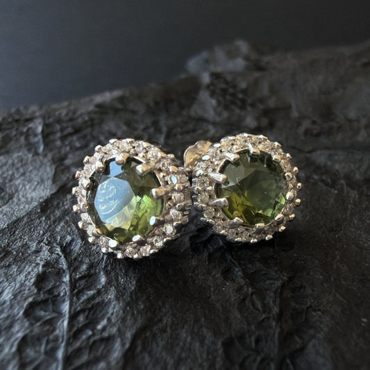 Pair of silver earrings with 6 mm Moldavites on a dark textured surface