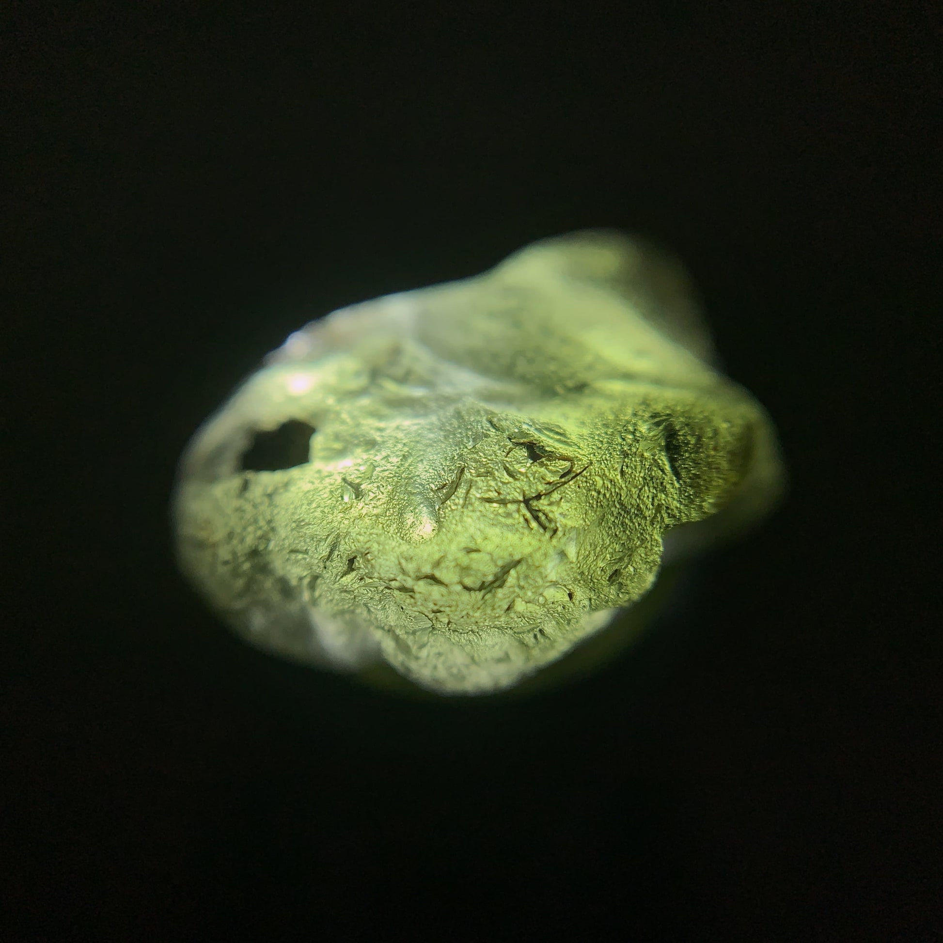Close-up of a raw moldavite crystal on a black background