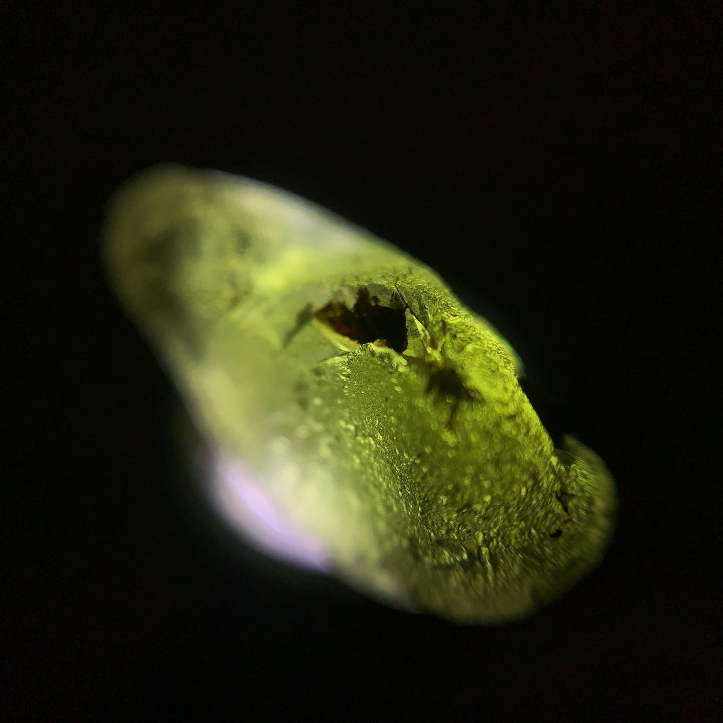 Close-up of a raw moldavite on a black background