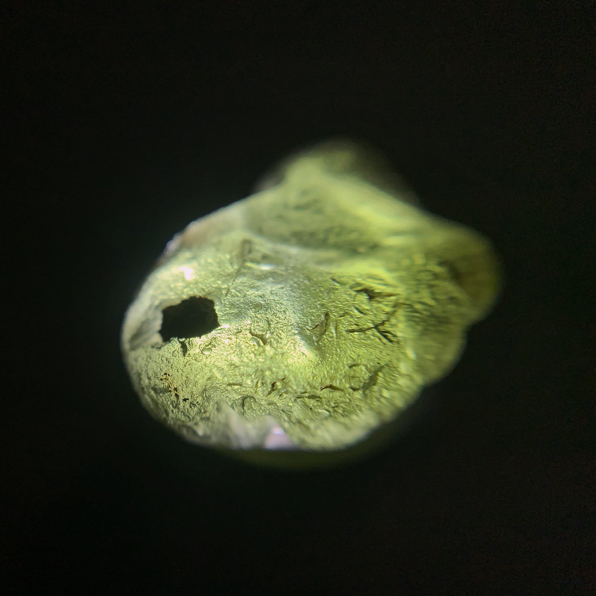Close-up of a raw moldavite on a black background