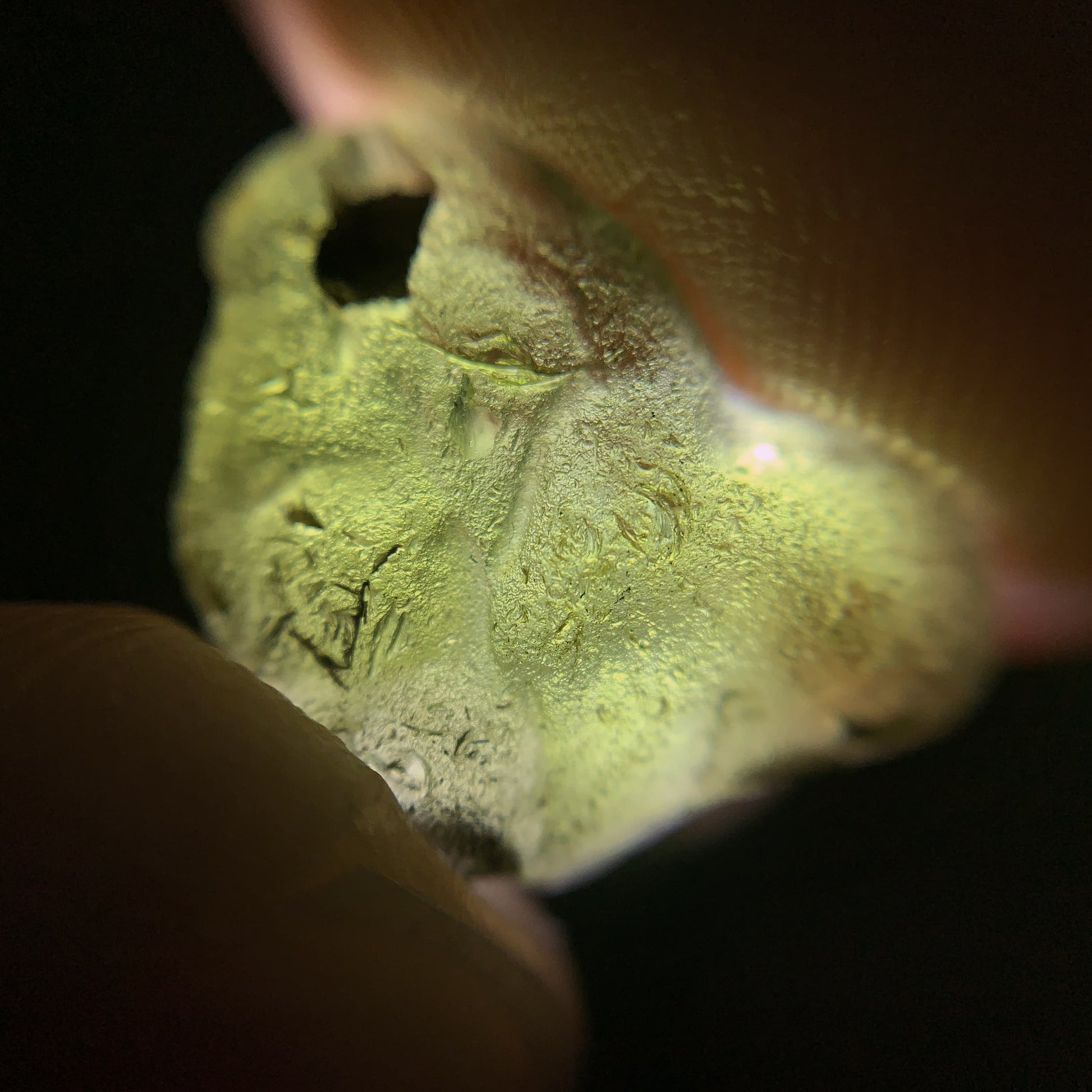 Close-up of a raw moldavite on a black background