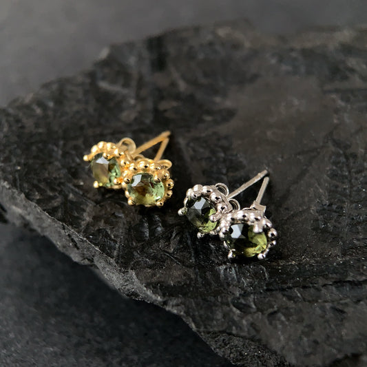 Pair of 18K gold plated and sterling silver stud earrings with 5mm real Moldavite stones and butterfly closures displayed on dark textured stone