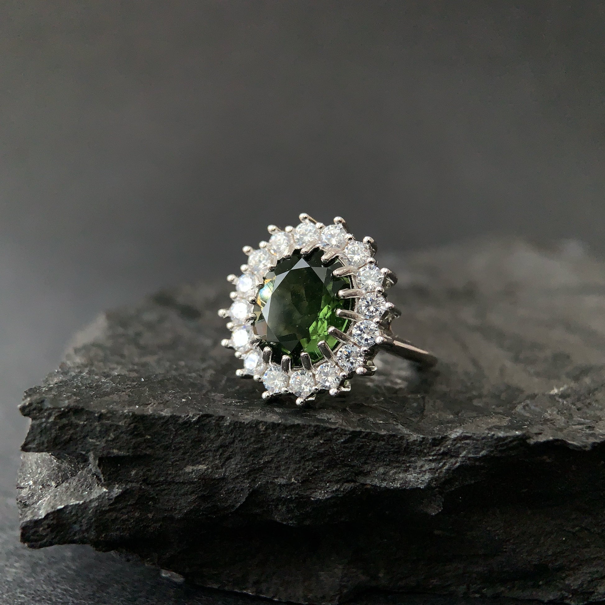 Silver ring with a oval moldavite on a dark stone surface