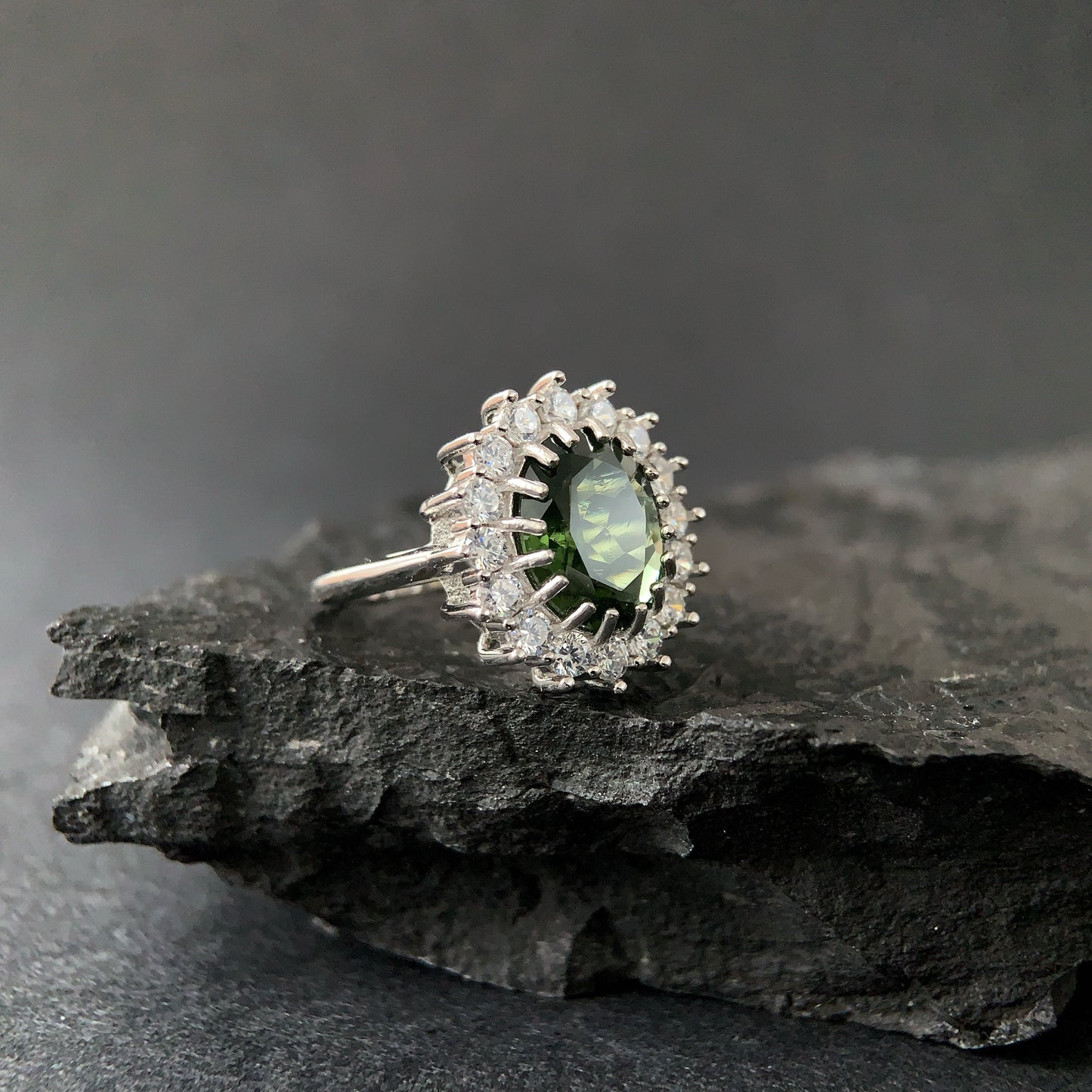 Silver ring with a oval moldavite on a dark stone surface