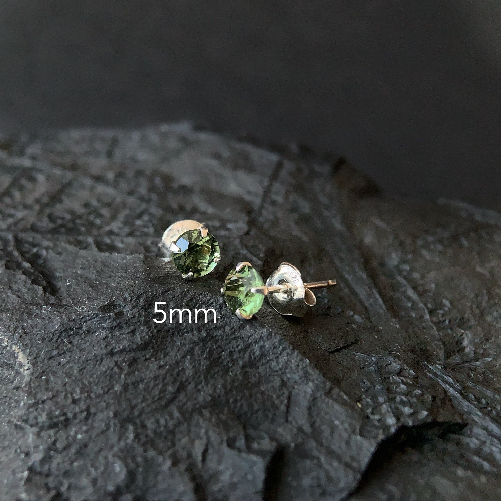 Moldavite stud earrings on a dark textured surface with '5mm' text.