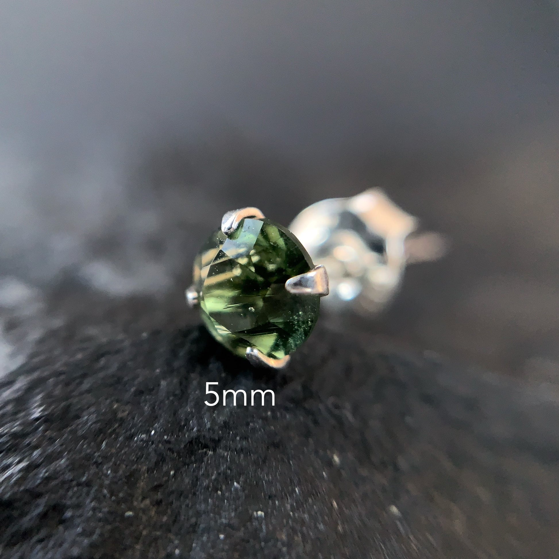 Macro shot of 5mm Moldavite earring on a dark surface
