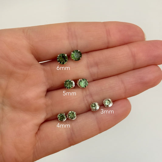 Moldavite earrings on a hand with size labels 3mm 4mm 5mm 6mm