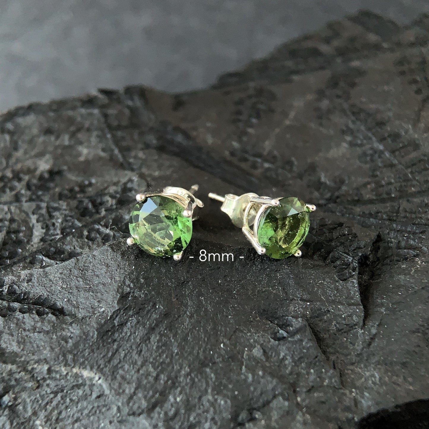 8 mm Moldavite stud earrings on a dark textured surface