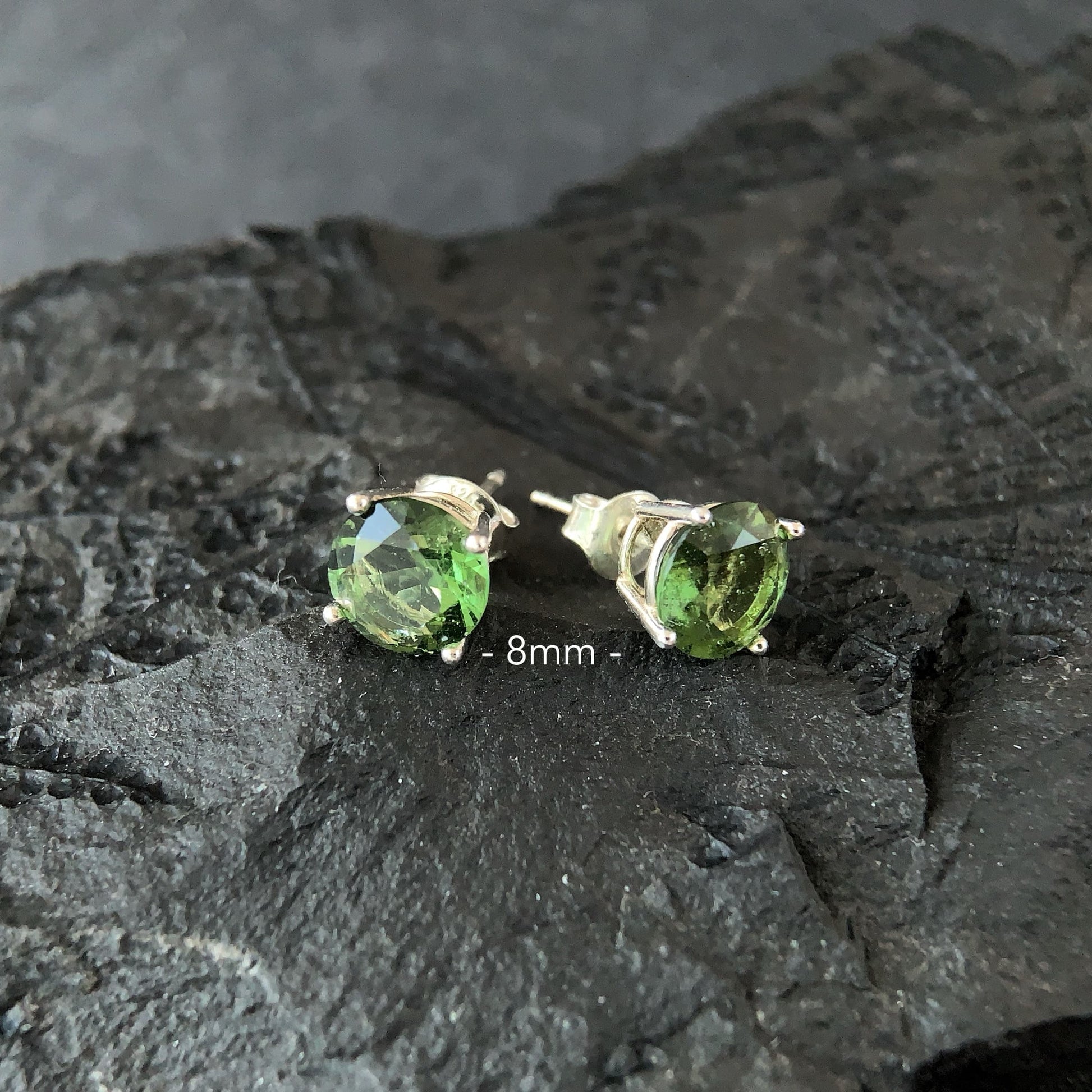 8 mm Moldavite stud earrings on a dark textured surface