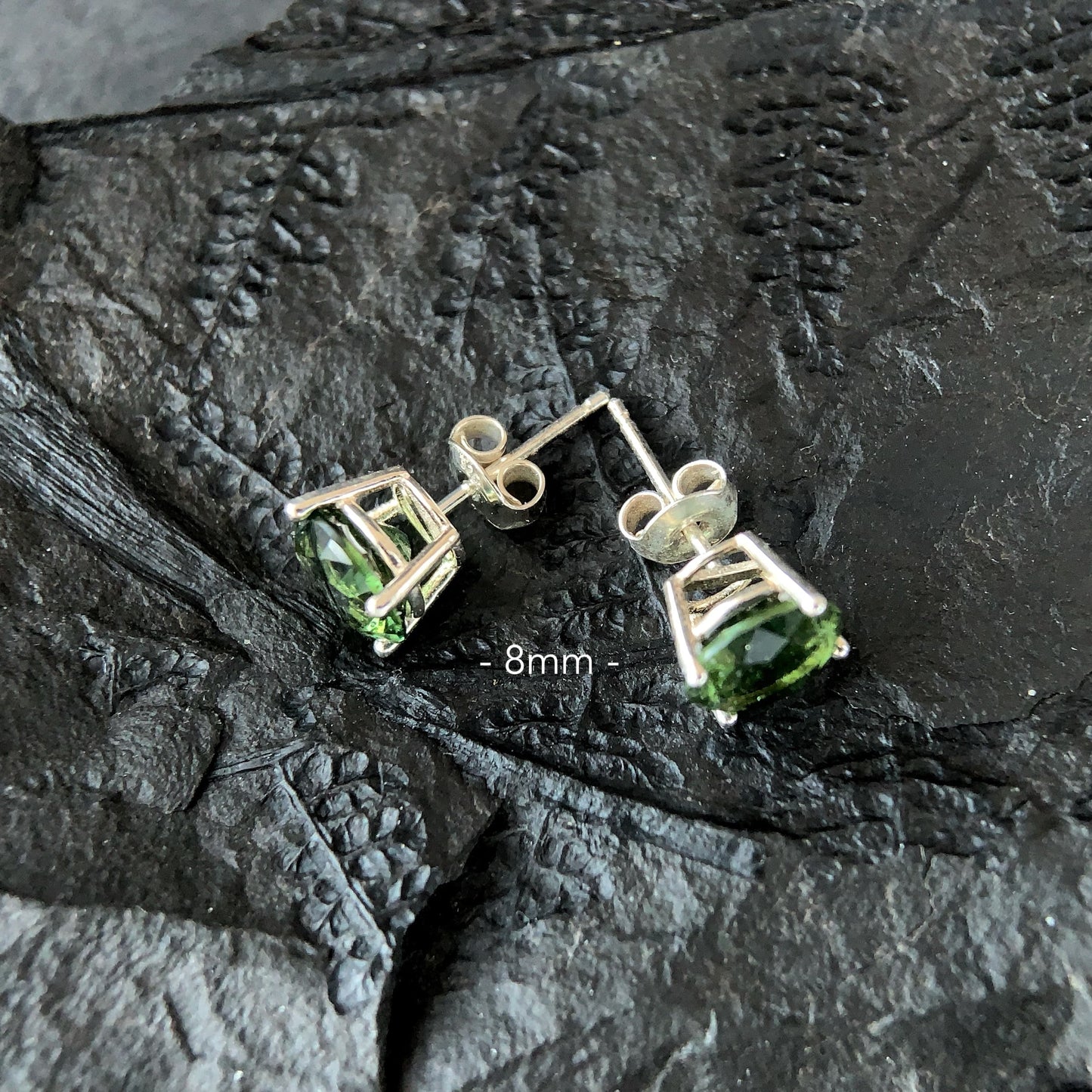 8 mm Moldavite stud earrings on a dark textured surface