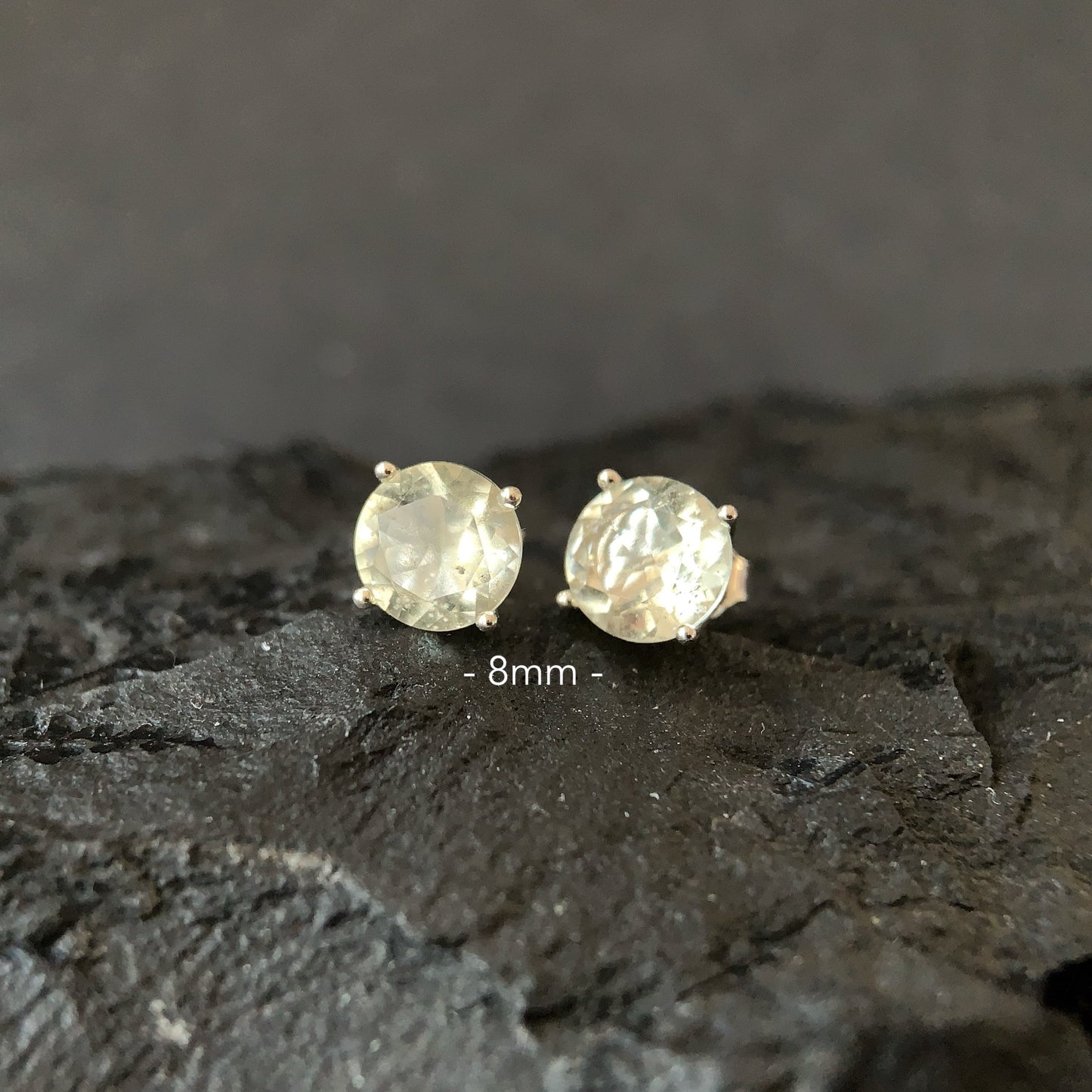 Pair of round Libyan desert glass stud earrings on a dark textured surface with '8mm' label.