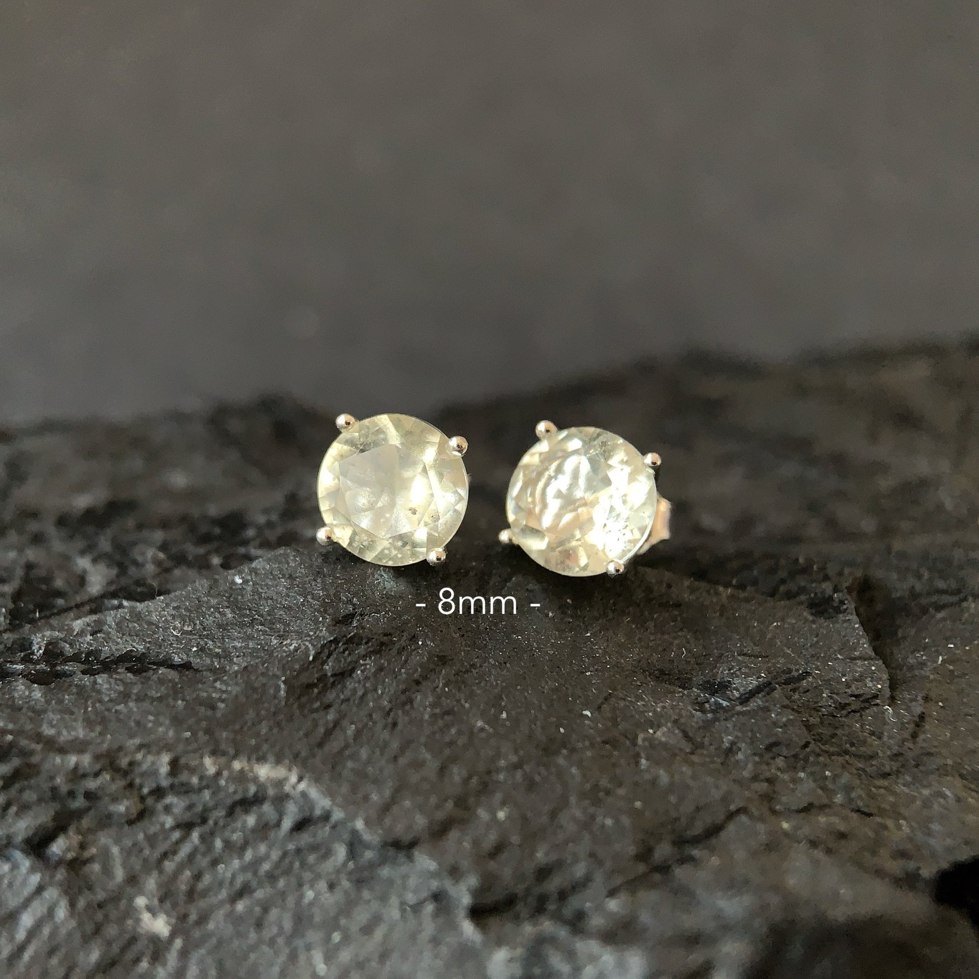 Pair of round Libyan desert glass stud earrings on a dark textured surface with '8mm' label.