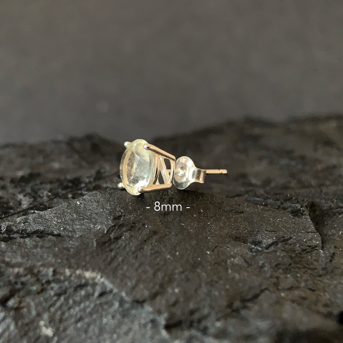 Libyan desert glass earring on a dark textured surface