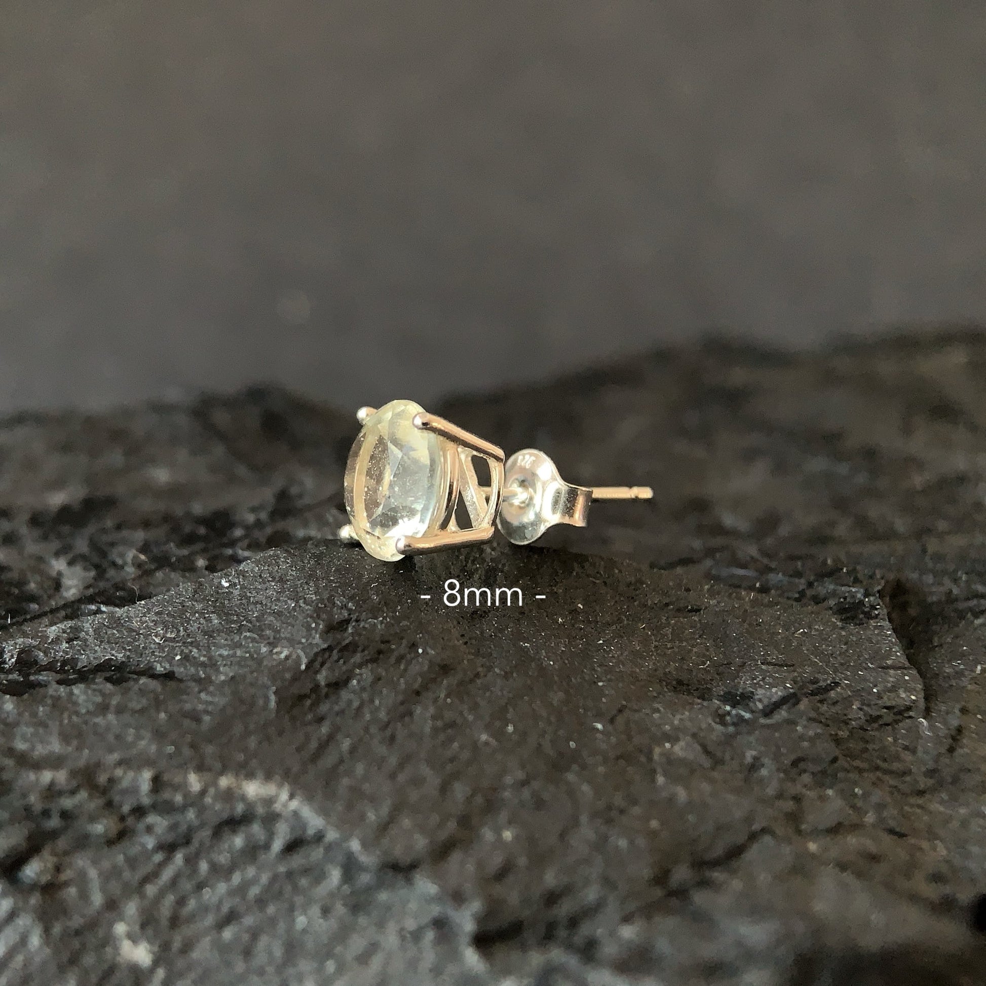 Libyan desert glass earring on a dark textured surface