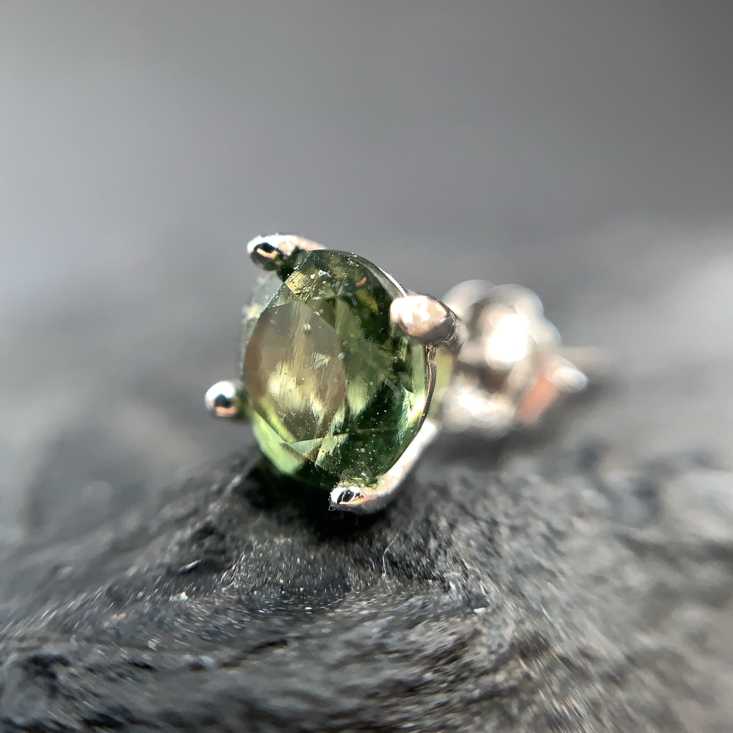 Close-up of a green gemstone earring on a dark surface