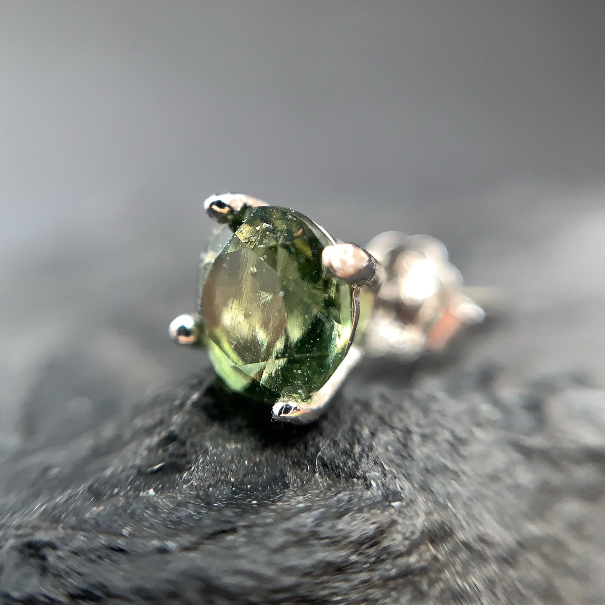 Close-up of a green gemstone earring on a dark surface