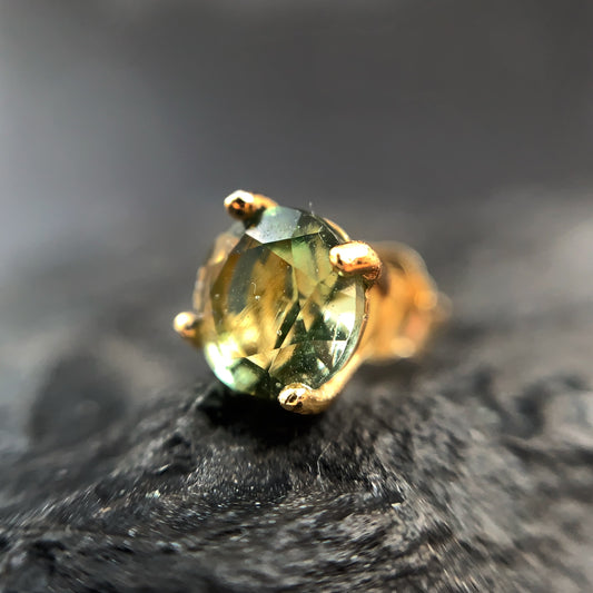 Gold plated earring with 6mm Moldavite on a dark textured surface